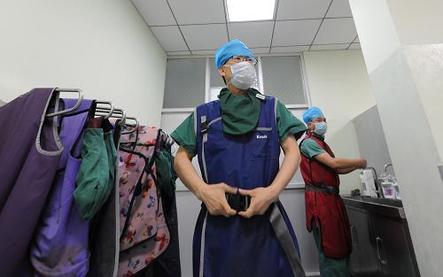 河南省人民医院心脏内科主任高传玉(左)在进入手术室前穿上铅衣(5月8日摄)。新华社记者 鹏 摄